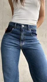 Pantalón de jean de tiro alto, color azul con detalles en azul oscuro en los bolsillos delanteros.