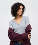 Cardigan de punto texturizado color gris, con escote en V, cierre frontal con botones y mangas largas.