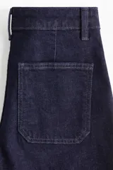 Pantalón de jean color azul marino, de tiro alto y corte wide leg, con amplios bolsillos frontales de parche y presillas para cinturón.