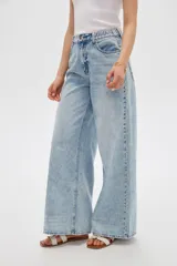 Pantalón jean de corte ancho y tiro alto, con lavado claro y cintura elástica posterior. Presenta bolsillos clásicos y presillas para cinturón.