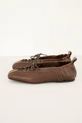 Mocasín marrón de cuero, con cordones frontales y diseño de corte bajo.