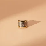 Anillo ancho de banda texturizada en plata con bordes lisos en oro, presenta una circonia central en forma de gota.