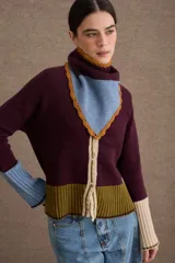 Cardigan de punto con diseño color block en tonos bordó, verde oliva y beige. Presenta cuello redondo con detalle en celeste, cierre frontal con botones y puños acampanados en color beige.