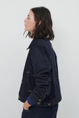 Chaqueta de pana color azul oscuro, con cuello camisero, cierre frontal con botones y bolsillos laterales. Diseño de corte recto y manga larga.