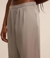 Pantalón de vestir color gris claro, de corte recto y tiro alto. Confeccionado en tejido sastrero de poliéster y elastano, con cierre lateral invisible y pliegues delanteros.