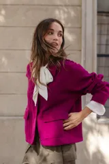 Chaqueta de lana afieltrada color amarillo, con cuello camisero, cierre frontal con broches a presión y bolsillos delanteros. Presenta un diseño de corte holgado con una apertura en la espalda que aporta movimiento.