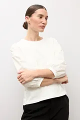 Remera blanca con mangas abullonadas y puños elásticos, de corte recto y escote redondo.