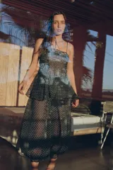 Top de tirantes finos con estampado de lunares, confeccionado en tejido semitransparente. Presenta detalles de encaje en el escote y un bajo asimétrico con volantes.