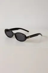 Lentes de sol con armazón ovalado de color negro y cristales tonalidad marrón. Presentan un detalle metálico en forma de estrella en las patillas.