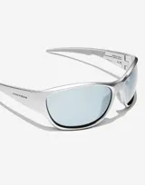 Lentes de sol unisex plateados, con montura rectangular envolvente y lentes espejadas celestes. Patillas con logo de Hawkers y detalle de texto en rojo.