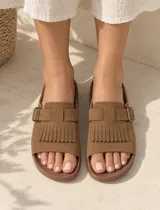 Sandalia negra de diseño destalonado con capellada ancha, detalle de flecos y tira con hebilla ajustable metálica.