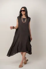 Vestido midi de lino color beige, sin mangas y con cuello redondo. Cuenta con un diseño irregular con detalle de volado vertical a un costado.