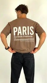 Remera de algodón color café, con cuello redondo, mangas cortas y corte holgado. Presenta un estampado tipográfico en el pecho con la palabra Paris.