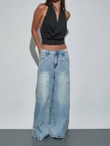 Jean de corte wide leg en color celeste, con diseño de lavado claro y detalle de tachas plateadas distribuidas por el frente.