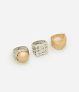 Kit de tres anillos de metal reciclado con efecto martillado. Incluye un anillo plateado con una esfera dorada, un anillo plateado cuadrado y un anillo dorado con forma irregular.