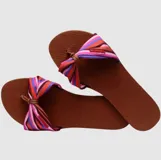 Sandalias tipo chinela Havaianas con base de goma azul marino y tira superior de tela con nudo central y estampado floral en tonos rosados y blancos.