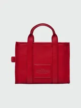 Bolso tipo tote de cuero negro, modelo The Leather Medium Tote Bag de Marc Jacobs. Presenta doble asa superior, correa ajustable para el hombro y el texto grabado "THE TOTE BAG MARC JACOBS" en el frente.