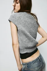 Jersey de punto gris jaspeado con cuello redondo y manga corta. Presenta detalles de encaje en los laterales.