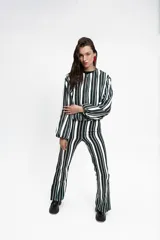 Campera tipo bomber corta, con cierre frontal, cuello a la base, bolsillos ojal y mangas largas abullonadas. Presenta un diseño estampado a rayas verticales en tonos blanco, negro y verde.