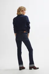Jean bootcut de color azul oscuro, con tiro medio, bolsillos frontales aplicados y costuras pespuntadas en contraste.