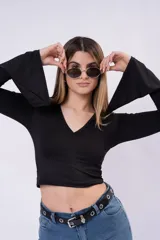 Remera corta negra de manga larga con diseño acampanado en los puños y escote en V.