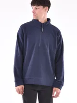 Buzo de polar color verde oliva, con cuello alto y cierre frontal parcial. Presenta puños y cintura acanalados.