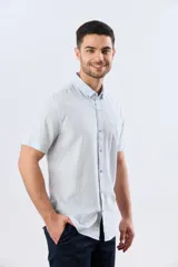 Camisa de lino de manga corta con diseño a rayas celestes y blancas, cuello camisero y cierre frontal de botones.