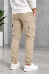 Pantalón cargo color beige de gabardina, con bolsillos laterales con solapa y puños elásticos en los tobillos.