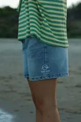 Short de jean celeste con logo estampado en blanco en la pierna izquierda.