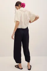 Pantalón negro de vestir de corte ancho y relajado, con cintura alta y detalles sutiles en el diseño.