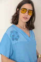 Blusa celeste de lino con escote en V, mangas cortas y detalle de bordado calado en el canesú.