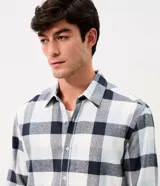 Camisa de corte comfort confeccionada en algodón, con estampado de cuadros en tonos marrón, beige y azul. Presenta cuello camisero, mangas largas con puños abotonados y cierre frontal con botones.