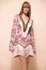 Vestido corto de estilo boho en tono rosa, con estampado floral, escote en V profundo decorado con cuentas y flecos, y mangas largas acampanadas.