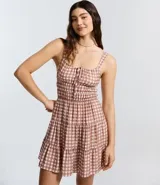 Vestido corto evasê de viscosa con estampado de cuadros vichy en tonos rosado y blanco. Presenta breteles anchos, escote cuadrado, lazo ajustable en el busto y falda con volados.