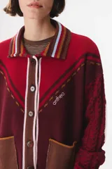Cardigan de punto con diseño multicolor, cuello tipo polo con rayas, cierre frontal con botones y bolsillos aplicados. Presenta mangas con trama trenzada, coderas en contraste y bordado de la marca en el frente.