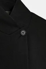 Blazer de lana con cuello subido, manga larga con botones en puños, bolsillos con solapa y bolsillo de vivo en el pecho. Cierre frontal con un botón.