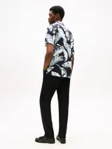 Camisa de hombre de corte regular con estampado de hojas en tonos azul y blanco sobre fondo negro. Tiene cuello cubano y manga corta.