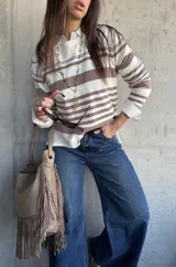 Sweater de punto fluido con diseño de rayas horizontales en color beige y blanco, de manga larga y silueta relajada.