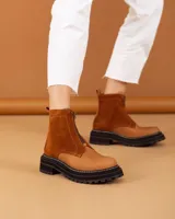 Botas de caña corta color beige, confeccionadas en cuero con textura granulada. Presentan cierre frontal central, suela track negra de goma con costuras blancas visibles y tirador en la parte trasera.