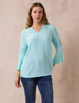 Blusa color celeste de gasa bambula con cuello a la base y escote en V. Manga ¾ amplia, con aplique en crochet.