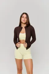 Campera deportiva de ajuste entallado, color marrón, con cuello alto, cierre frontal completo y mangas largas con aberturas para pulgares.