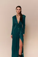 Vestido largo de lentejuelas color negro, con escote profundo en V, mangas largas y tajo lateral en la falda. Presenta un diseño cruzado con fruncido en la cintura y espalda elastizada.