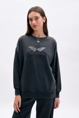 Buzo oversize negro con efecto desgastado, cuello redondo y estampado frontal de alas con la frase "Wild Hearts".