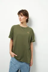 Remera negra de corte oversize con cuello redondo y manga corta. Presenta un pequeño estampado dorado en el pecho con la frase "love earth" y un símbolo de hojas.