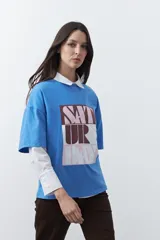 Remera de manga corta con corte boxy fit, color blanco, con estampa frontal geométrica en tonos azul, rosado y marrón.