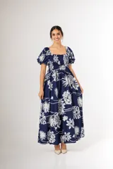 Vestido largo azul marino con estampado floral blanco, escote cuadrado con nido de abeja en el pecho y mangas abullonadas cortas.