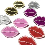 Par de aros con forma de labios negros con glitter y borde plateado.