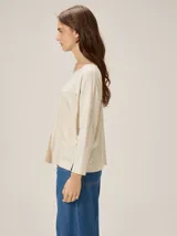 Remera de silueta relajada con diseño de paneles en tonos beige y crema, cuello redondo y mangas tres cuartos.