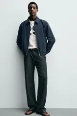 Cazadora boxy fit color azul marino, confeccionada en tejido de algodón. Presenta cuello solapa, manga larga con puño abotonado, bolsillos de vivo en la cadera y bajo elástico. Cierre frontal con cremallera.