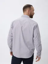Camisa de corte clásico confeccionada en tejido Oxford de algodón, con cuello abotonado, manga larga y bolsillo frontal en el pecho.